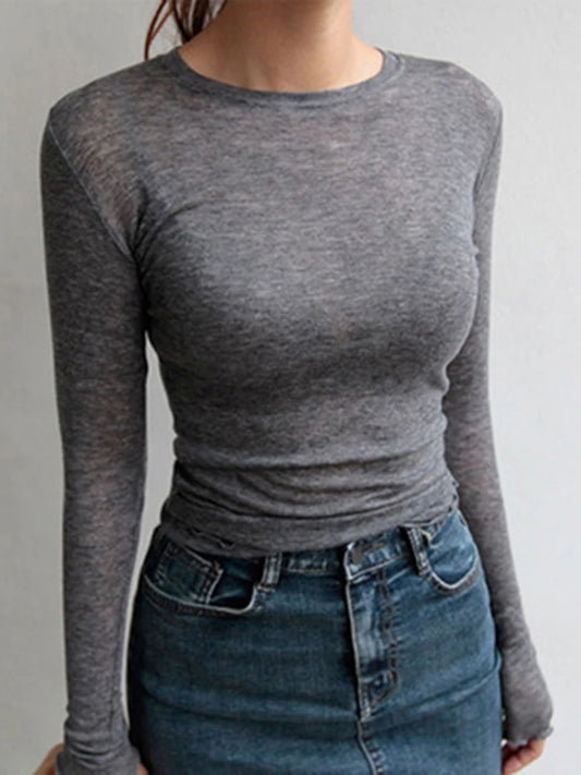 Person wearing a gray long-sleeve top and blue jeans against a plain background